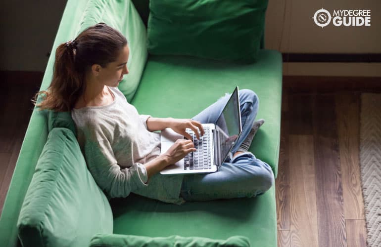 Information Technology student studying on her laptop in a sofa