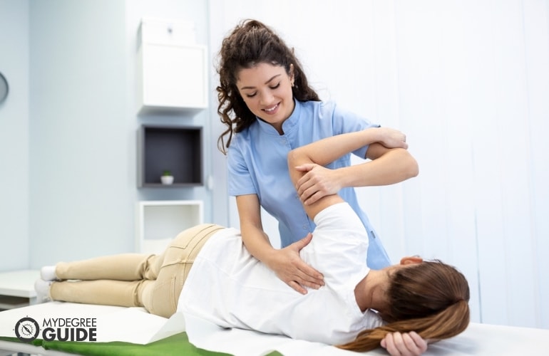 orthopedist massaging middle-aged woman in a clinic
