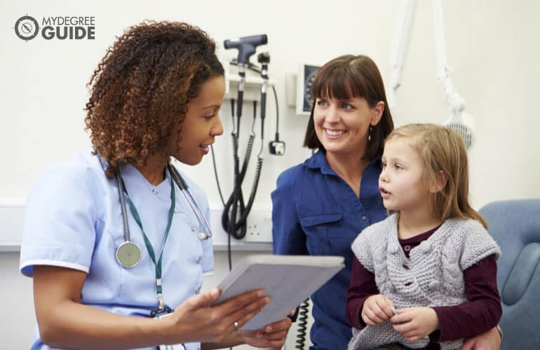 nurse talking to a child and his parent in a clinic