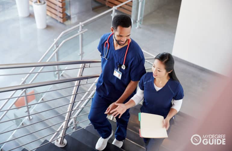 nurses talking to each other while walking on the stairs of a hospital