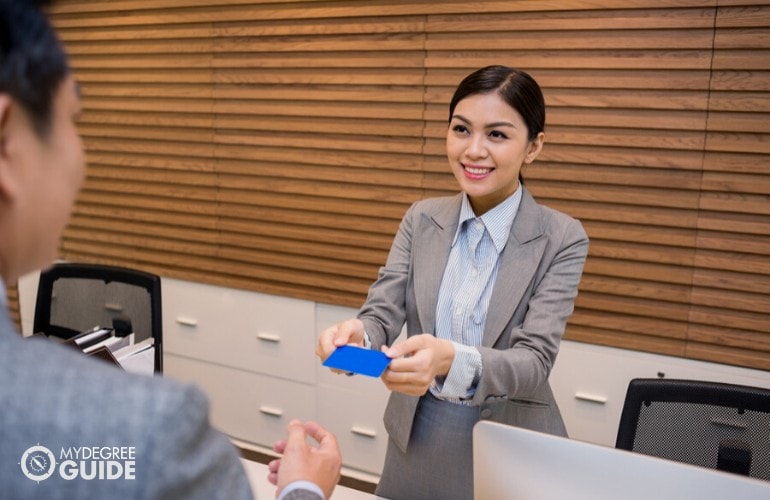 female hotel receptionist handing key card to guest