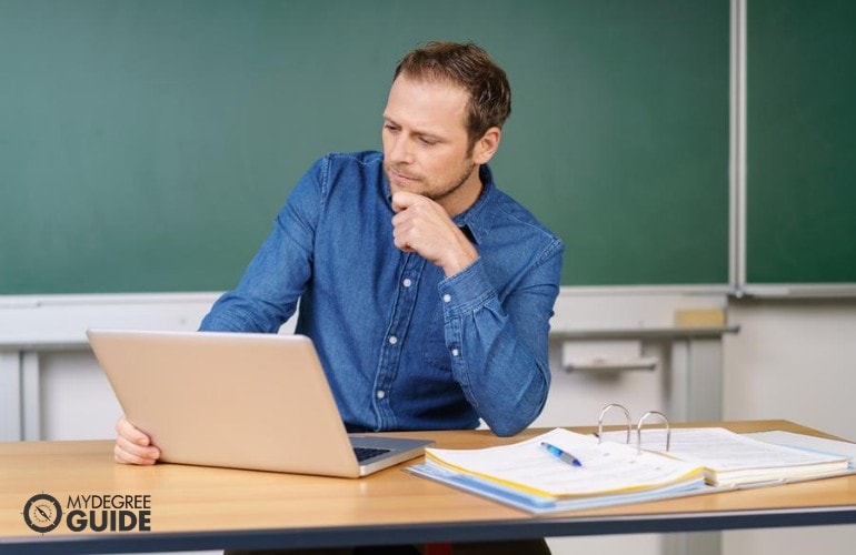 university professor working on his laptop in classroom