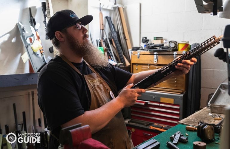 Gunsmith inspecting guns for safety hazards