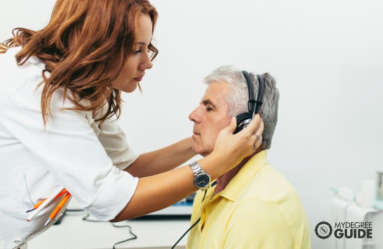 Hearing Aid Specialist diagnosing hearing problems on an elderly