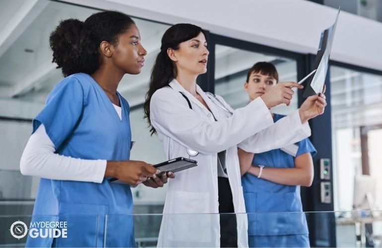 Medical assistants taking notes of doctor’s analysis