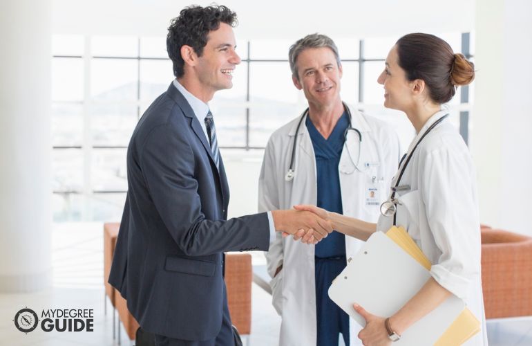 Healthcare services manager greeting two doctors